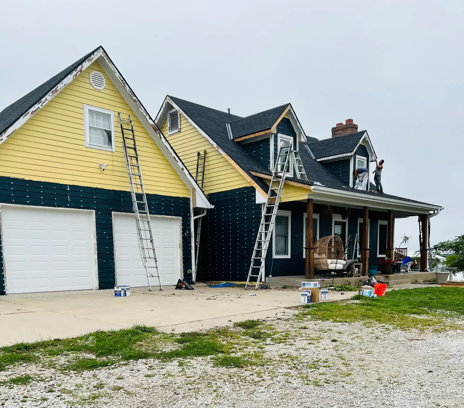 Farmhouse being painted from yellow to navy