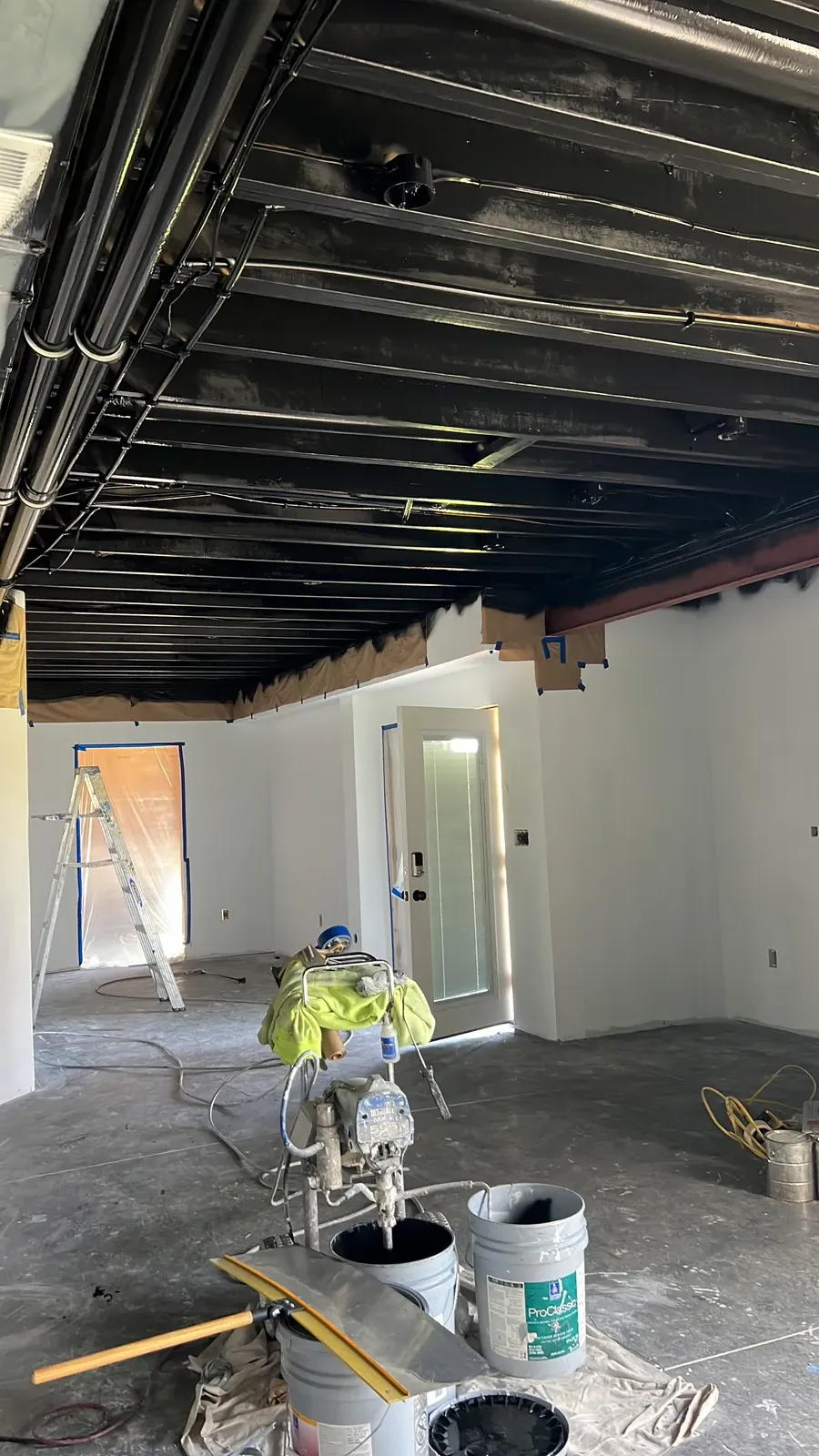 Black office ceiling being spray painted